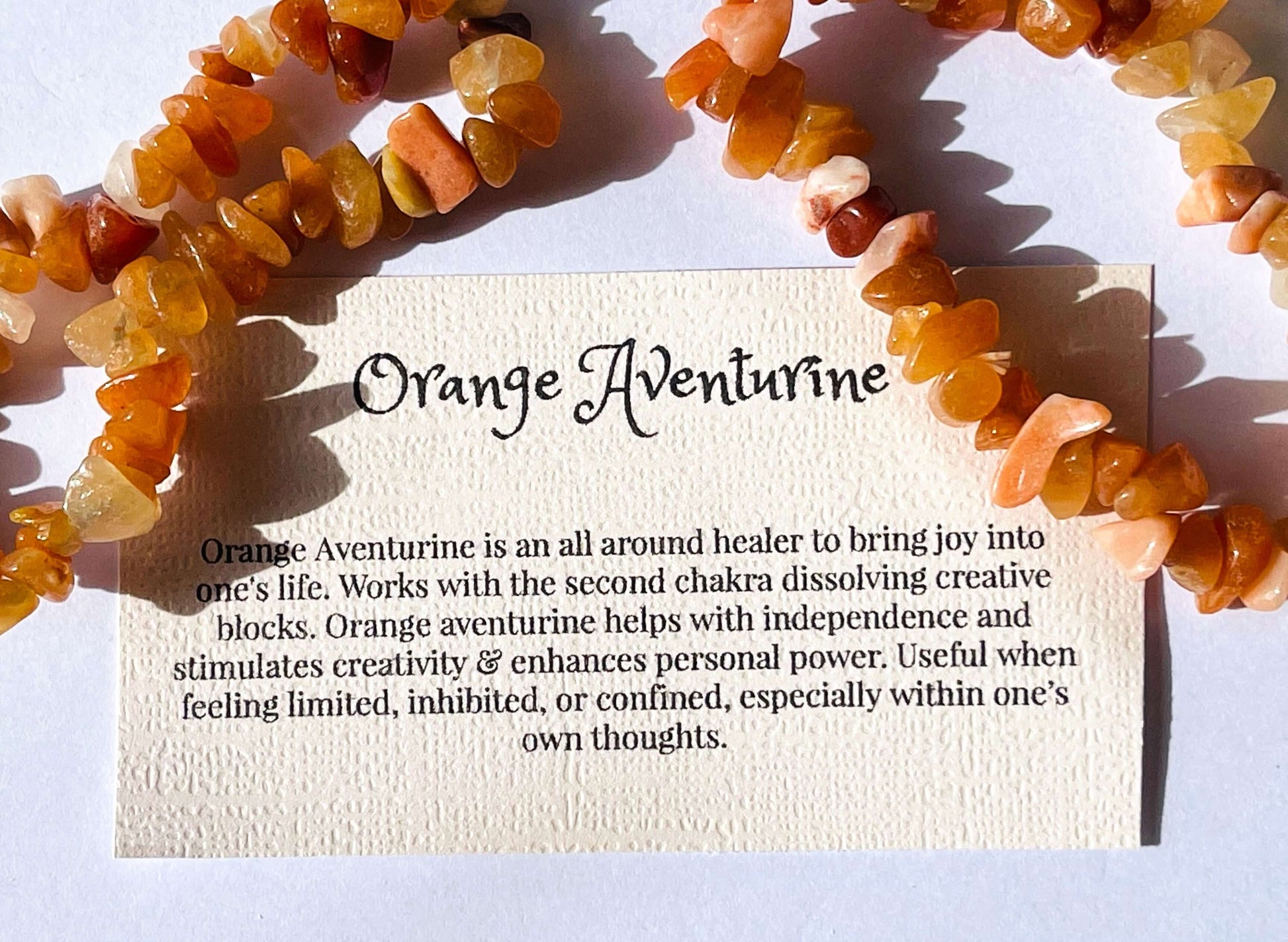 Orange aventurine crystal chip bracelet with information card on white background