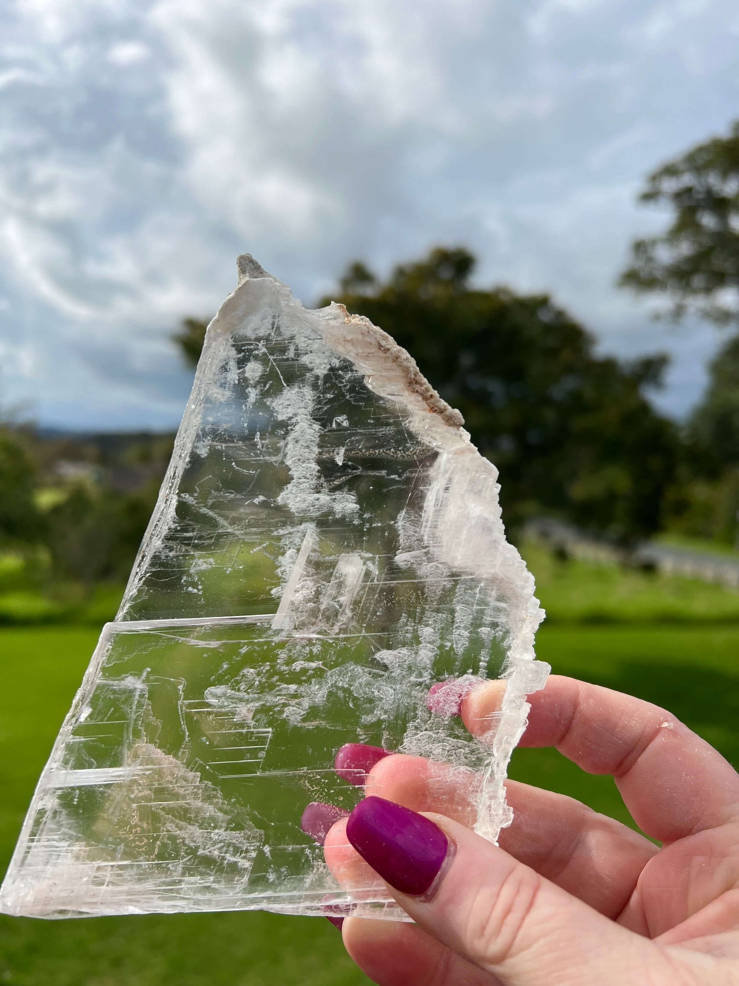 Clear selenite crystal slab with farm land in background