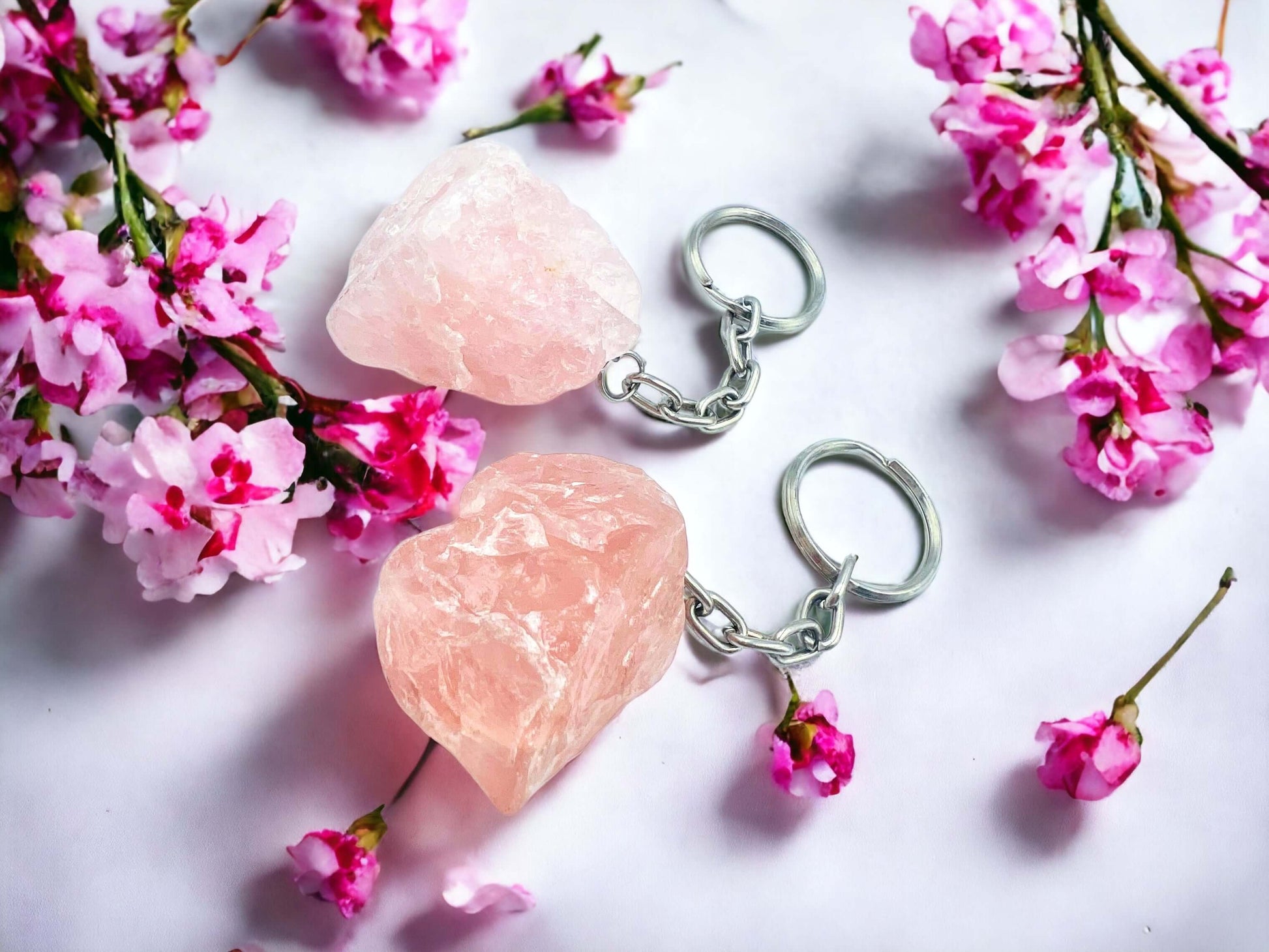 Crystal key rings on white surface with petals