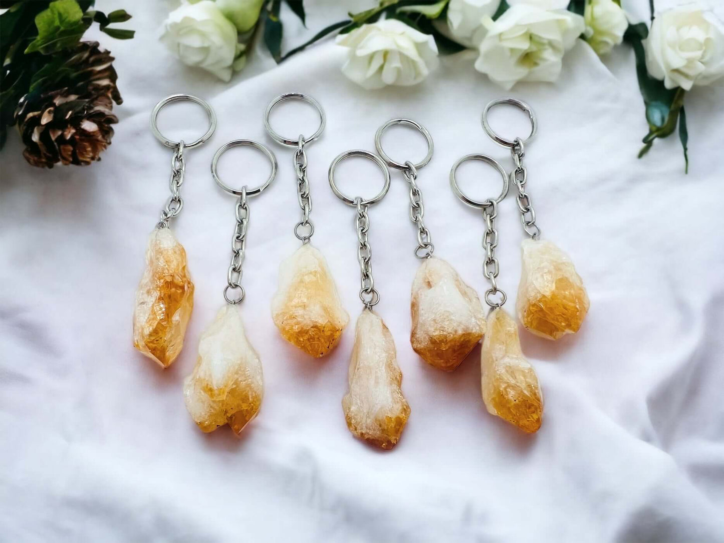 Crystal key rings on white surface with petals