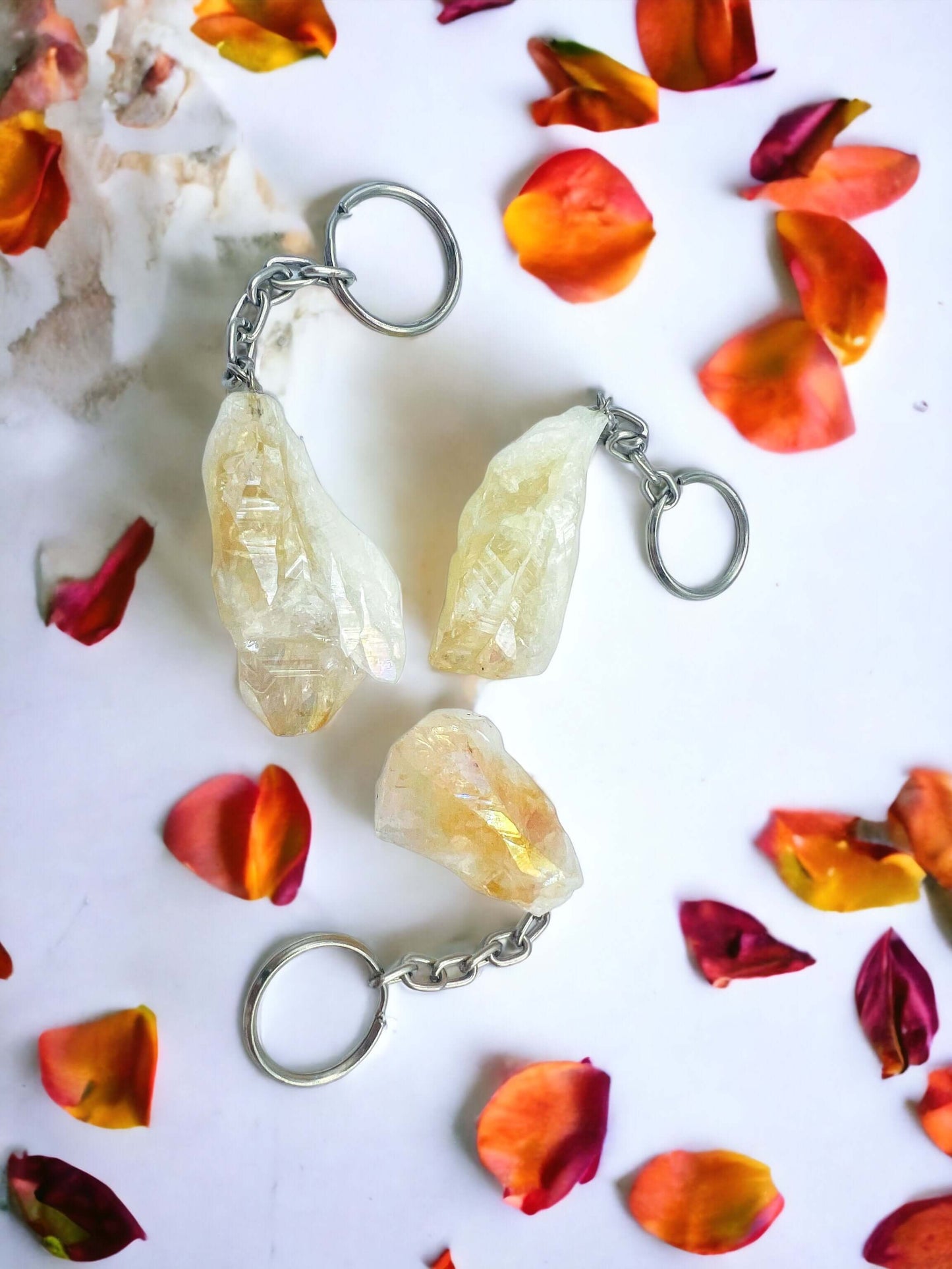 Crystal key rings on white surface with petals