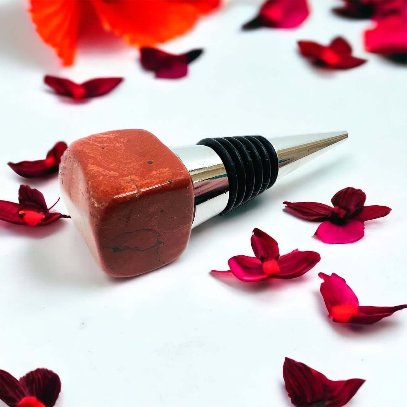 Red Jasper wine bottle stoppers on white surface with petals