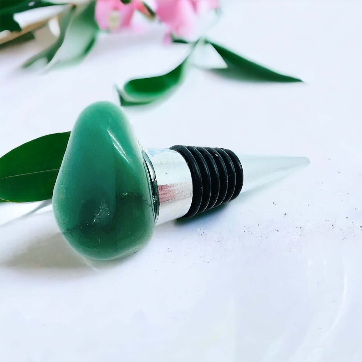 Aventurine wine bottle stoppers on white surface with petals