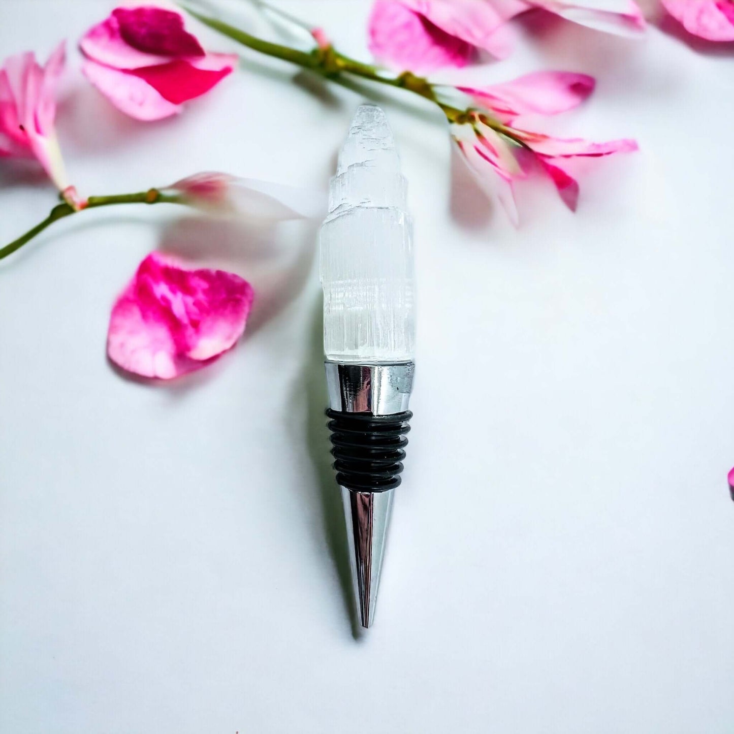 Selenite wine bottle stoppers on white surface with petals