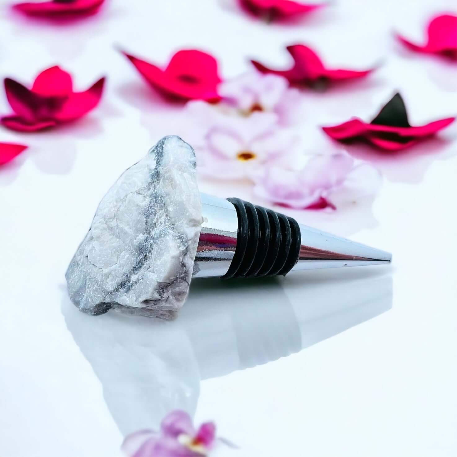 Howlite wine bottle stoppers on white surface with petals