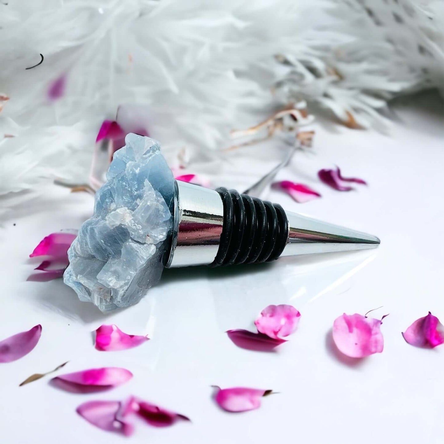 Blue calcite wine bottle stoppers on white surface with petals