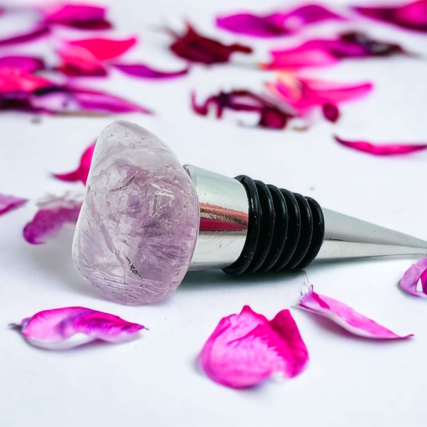 Amethyst wine bottle stoppers on white surface with petals