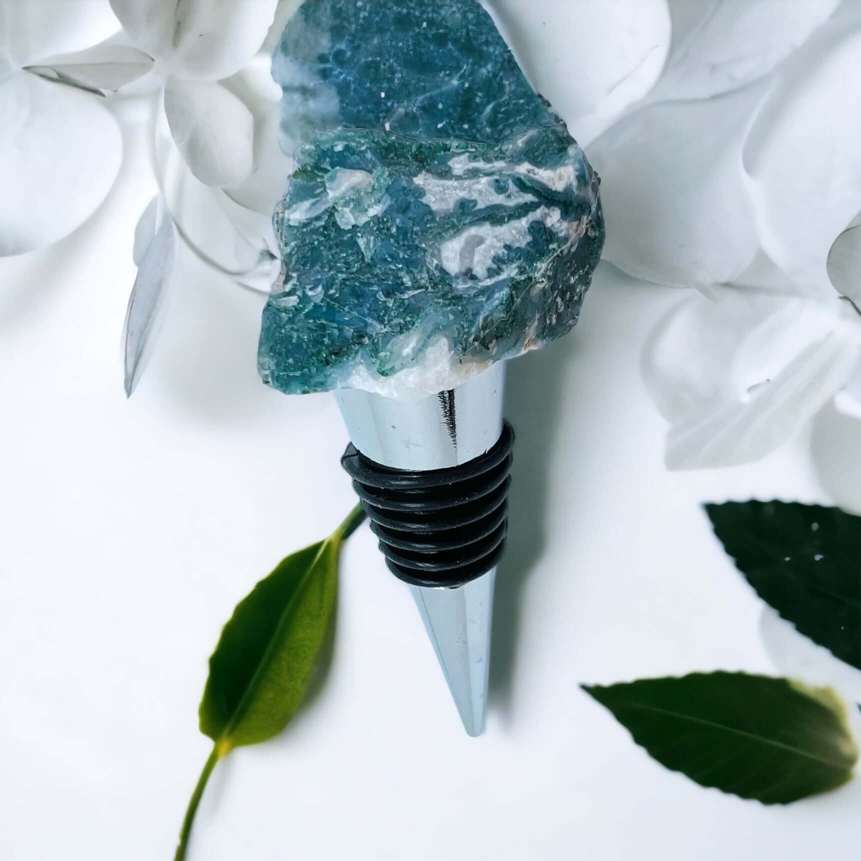 Moss agate wine bottle stoppers on white surface with petals